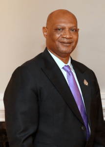 A man in a suit and tie standing next to a wall.